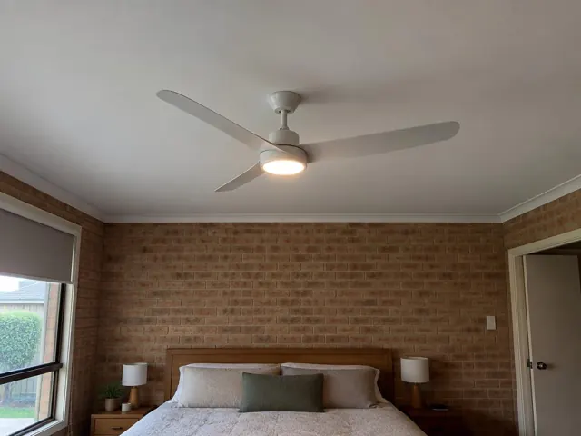 Ceiling fan on a white ceiling above a brick bedroom wall and bed in Hamlyn Terrace